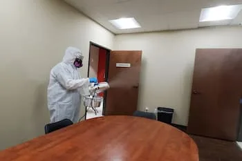 COVID-Cleaning-Service A worker for My Angel Maids sprays disinfectant on a boardroom